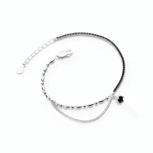 Silver bracelet with a small black heart charm and black stones in one side on a white background