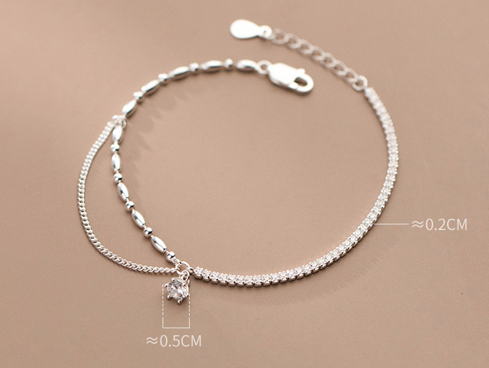 Silver anklet with a small white charm on a beige background with stone sizes specifications