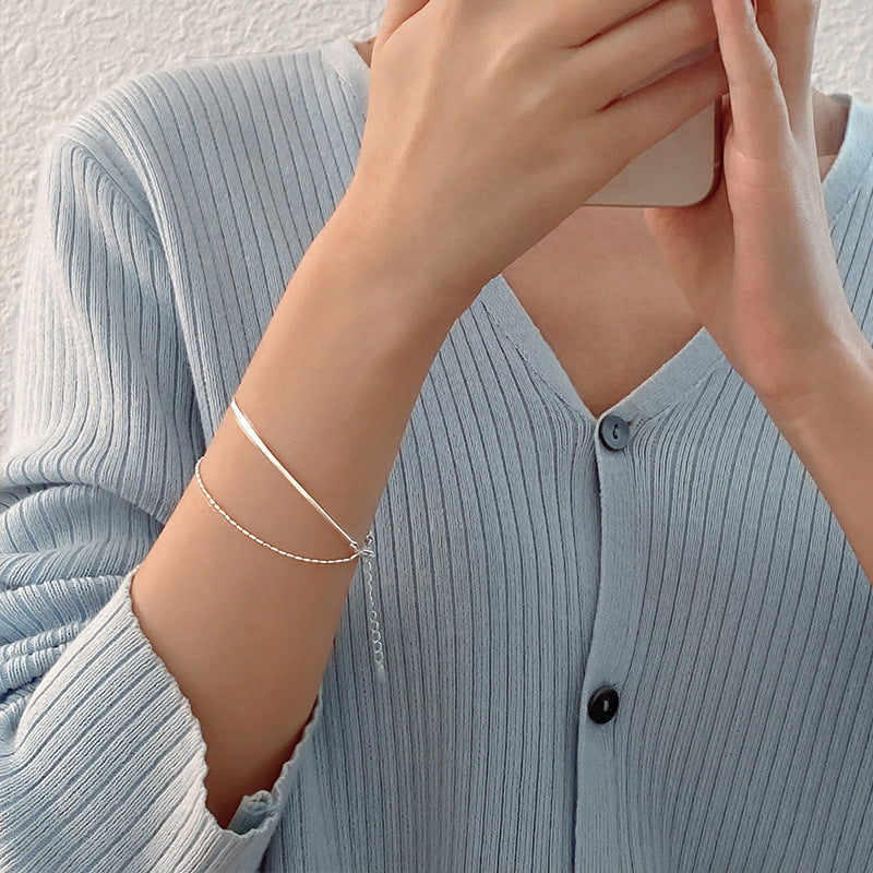 Person wearing a silver bracelet on a light blue ribbed sweater.