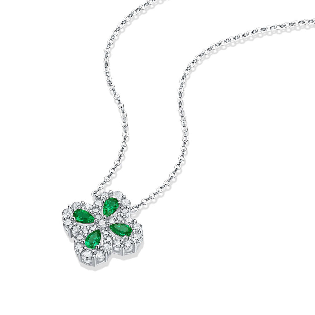 Silver necklace with a flower-shaped pendant featuring green gemstones on a white background