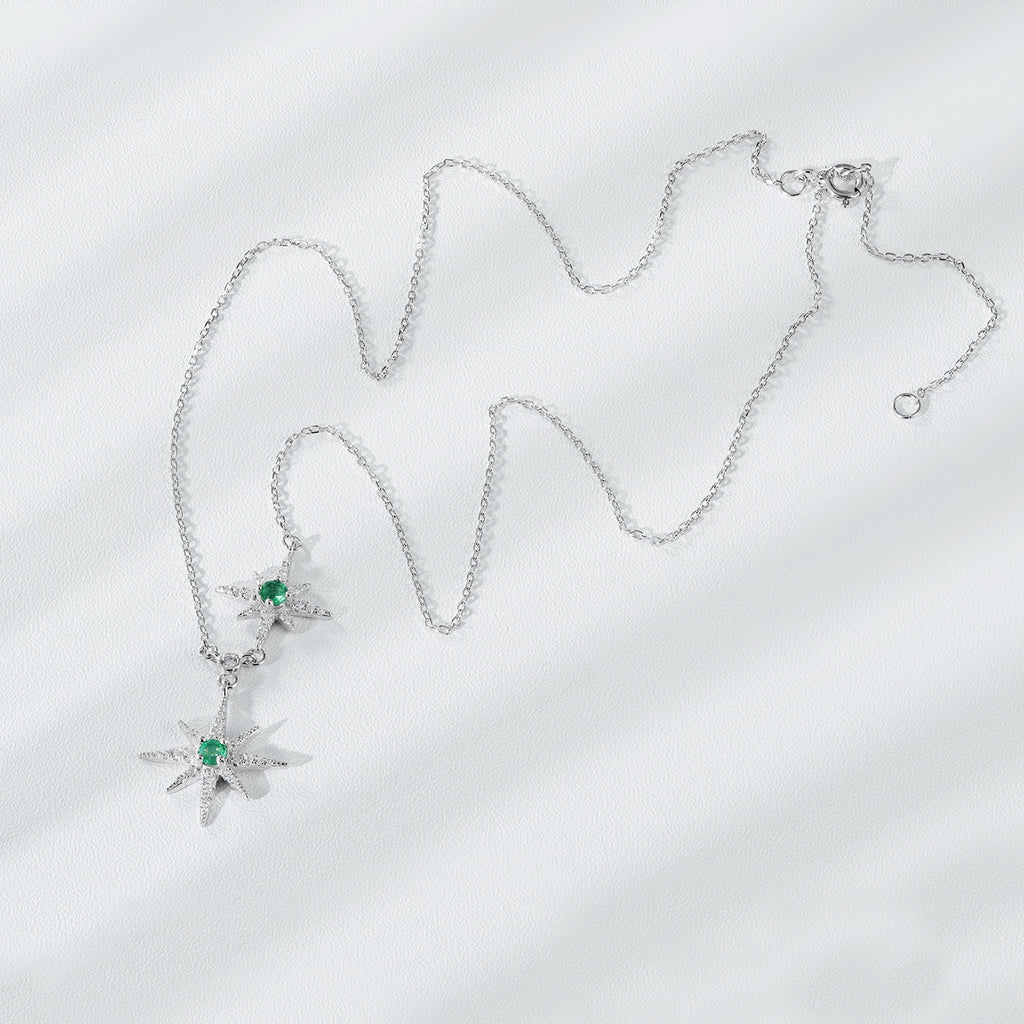 Silver necklace with star-shaped pendants on a light gray background