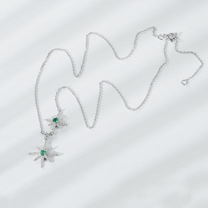 Silver necklace with star-shaped pendants on a light gray background