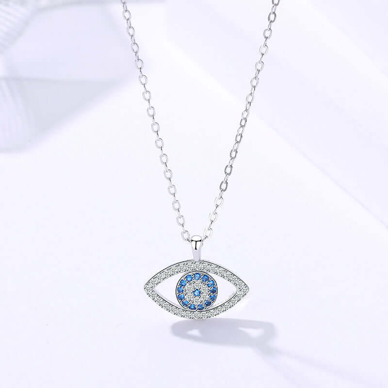Silver necklace with an eye-shaped pendant featuring blue stones on a white background