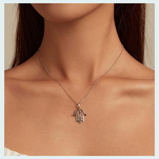 Silver Fatima hand necklace on a person's neck against a neutral background