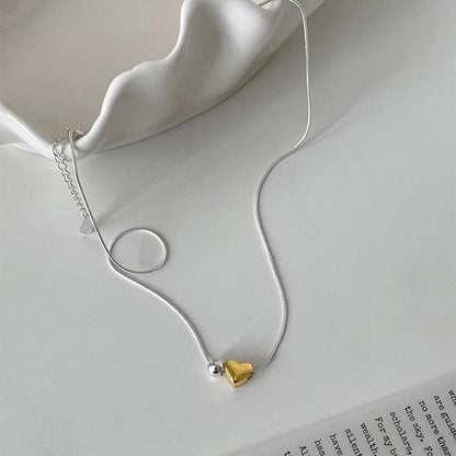 Necklace with a gold heart pendant on a white surface