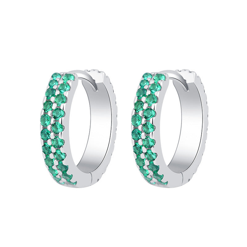 Silver hoop earrings with green gemstones on a white background