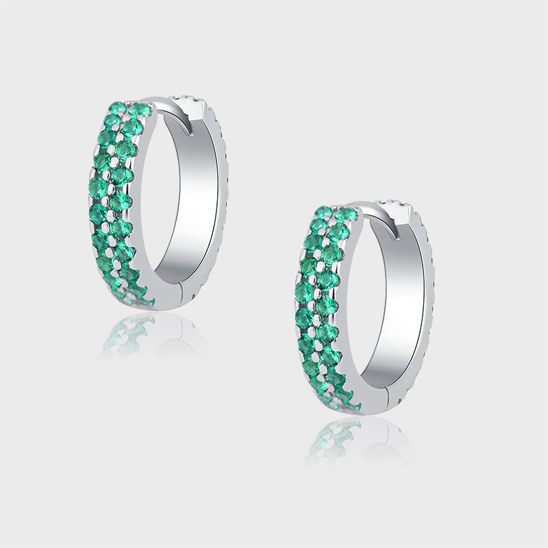 Pair of silver hoop earrings with green gemstones on a light gray background