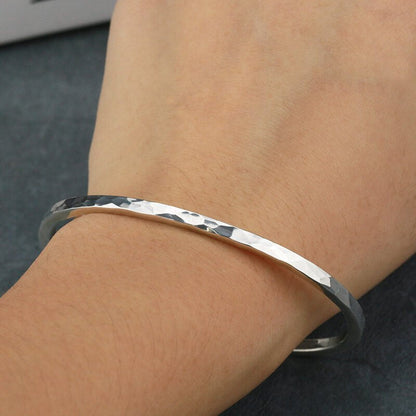 Silver bracelet on a wrist with a dark background