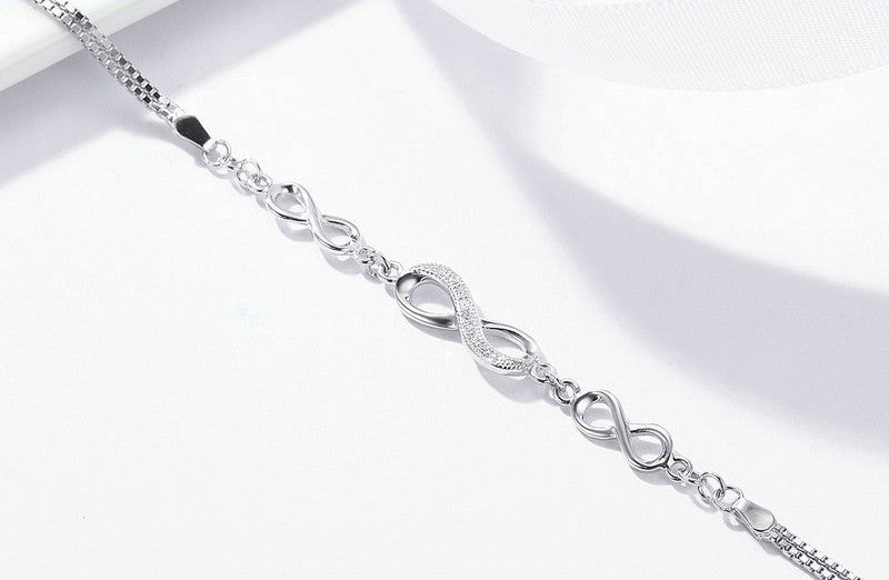 Silver bracelet with infinity symbol design on a white background