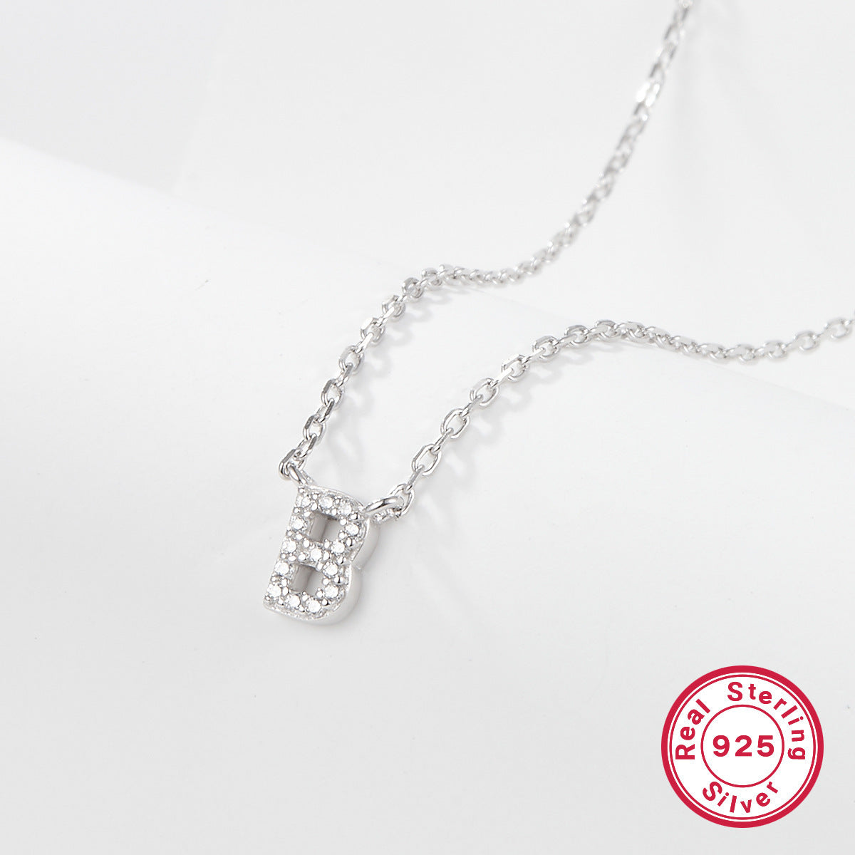 Silver necklace with a letter 'B' pendant on a white background, featuring a 'Real Sterling Silver 925' stamp.