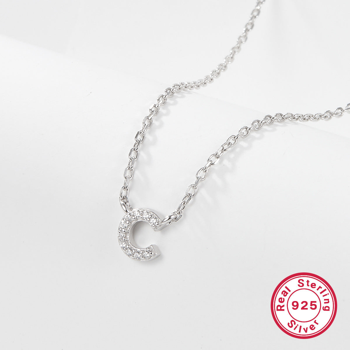 Silver necklace with a letter 'C' pendant on a white background, featuring a 'Real Sterling Silver 925' stamp.