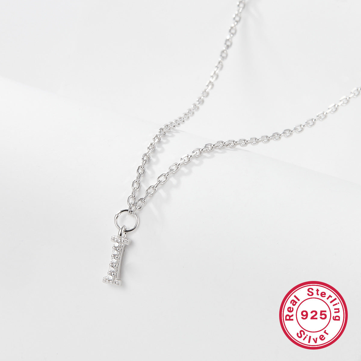 Silver necklace with a letter 'I' pendant on a white background, featuring a 'Real Sterling Silver 925' stamp.