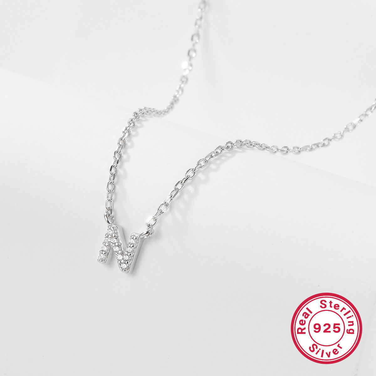 Silver necklace with a letter 'N' pendant on a white background, featuring a 'Real Sterling Silver 925' stamp.