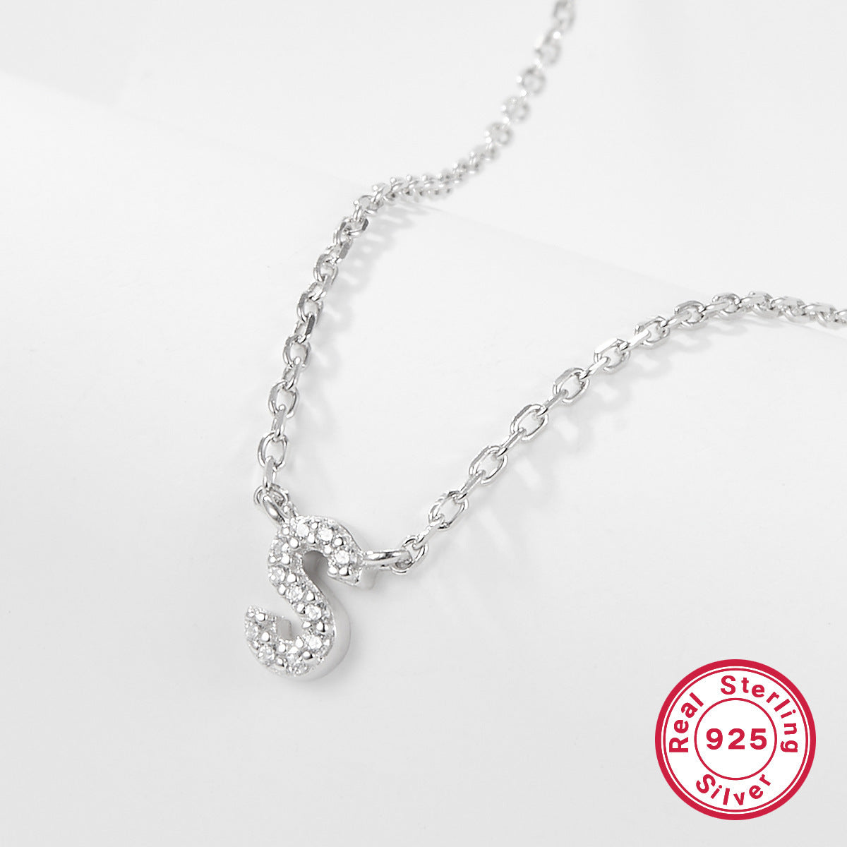Silver necklace with a letter 'S' pendant on a white background, featuring a 'Real Sterling Silver 925' stamp.