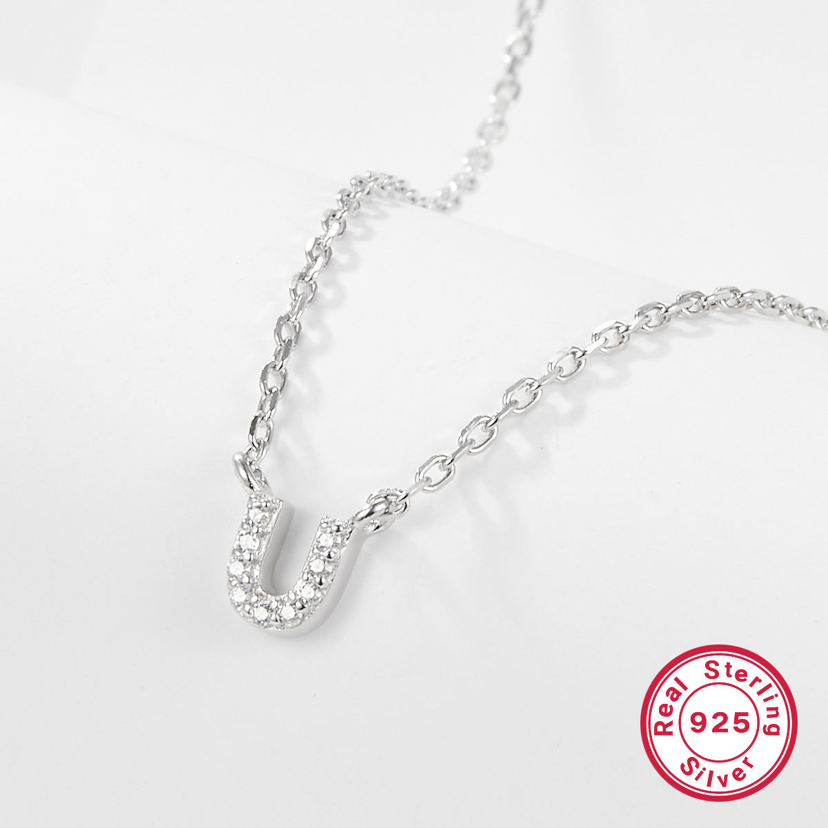 Silver necklace with a letter 'U' pendant on a white background, featuring a 'Real Sterling Silver 925' stamp.