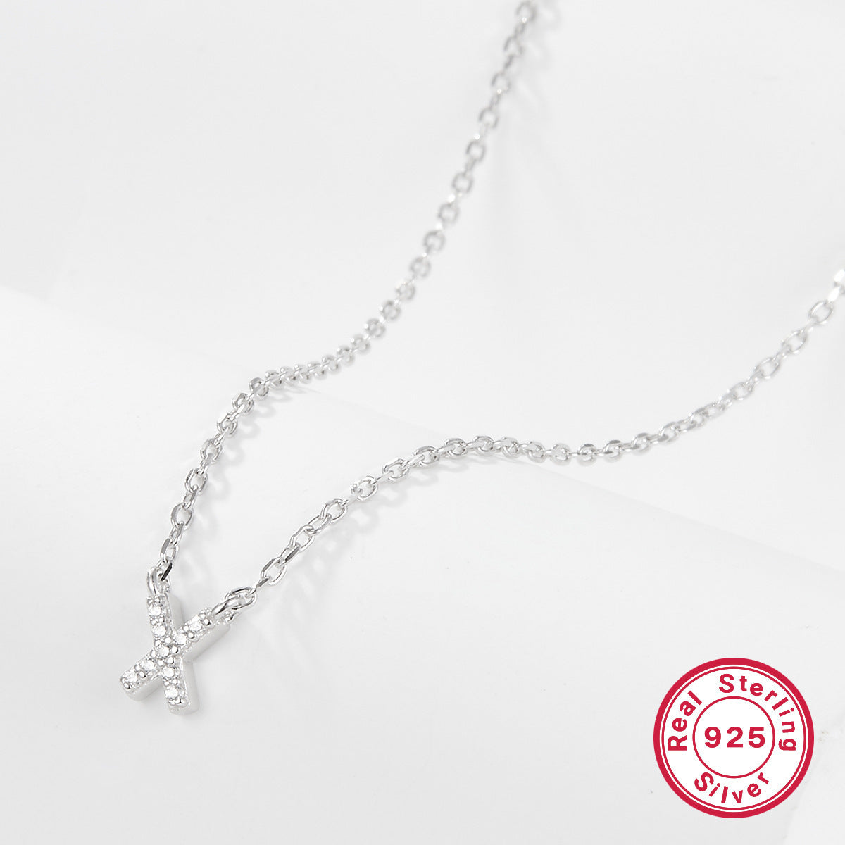 Silver necklace with a letter 'X' pendant on a white background, featuring a 'Real Sterling Silver 925' stamp.