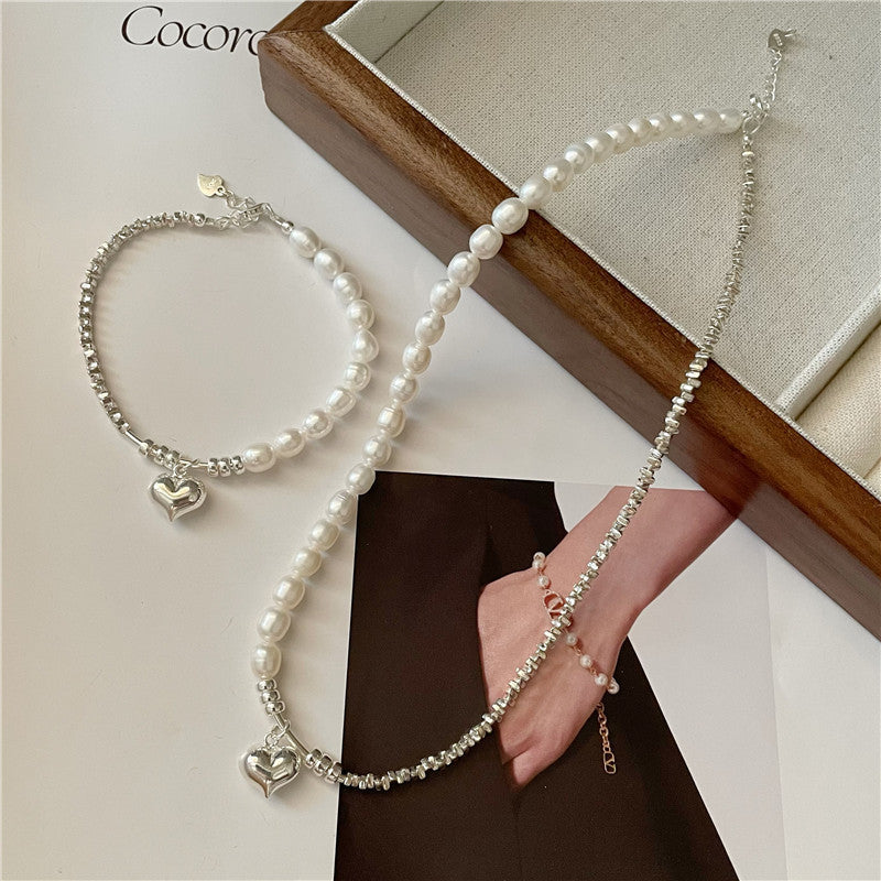 Pearl necklace and bracelet with heart-shaped charms and silver beads on a neutral background