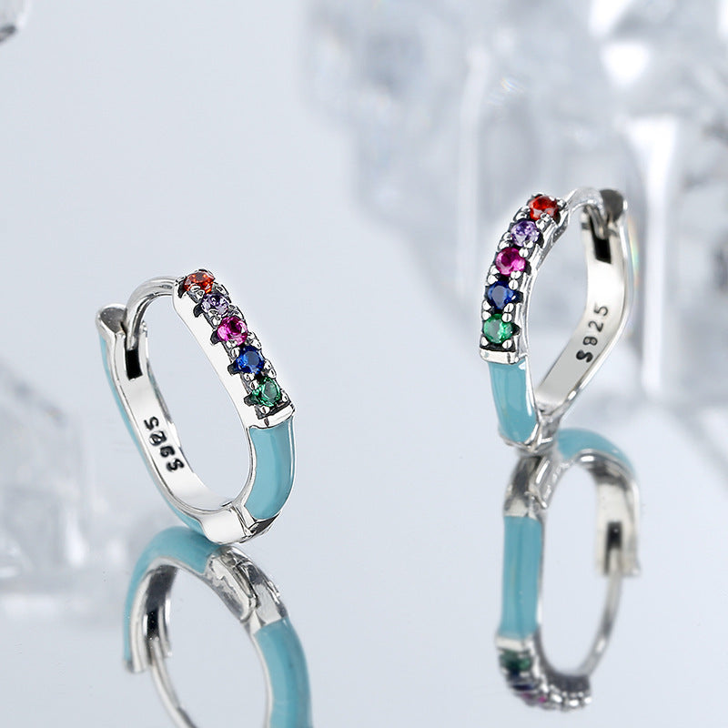 Pair of hoop earrings with colorful gemstones on a light gray background