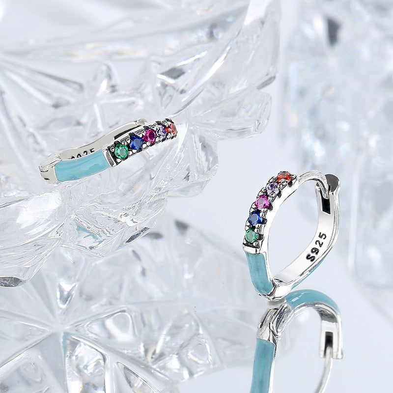 Silver earrings with colorful gemstones on a textured white background