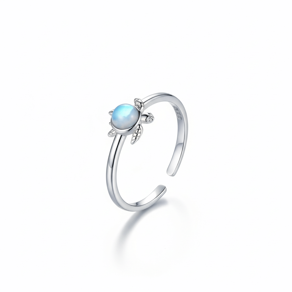 Silver ring with  a turtle shape on it and blue gemstone on a white background