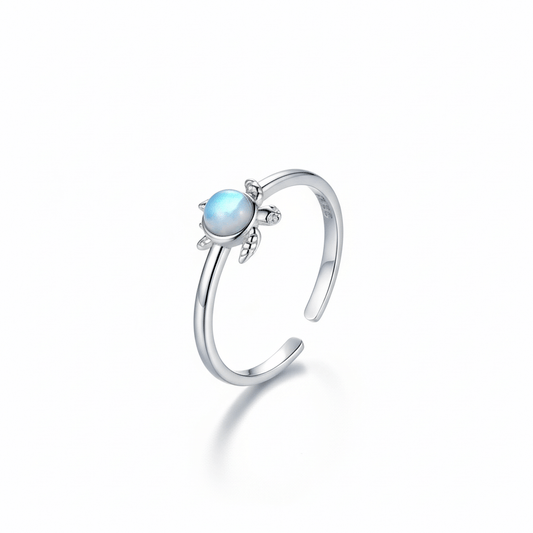 Silver ring with  a turtle shape on it and blue gemstone on a white background
