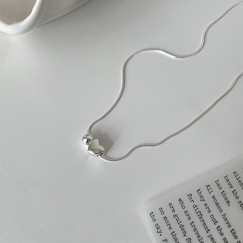 Silver necklace with a silver heart pendant on a white surface