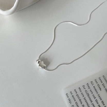 Silver necklace with a silver heart pendant on a white surface