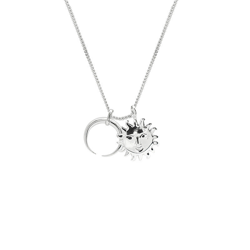 Silver necklace with sun and moon pendants on a white background