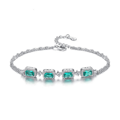 Silver bracelet with emerald green gemstones on a white background