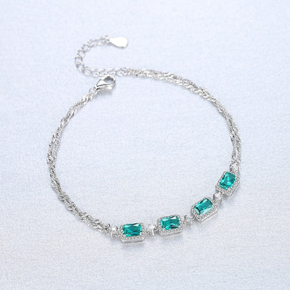 Silver bracelet with green emerald stones on a grey background
