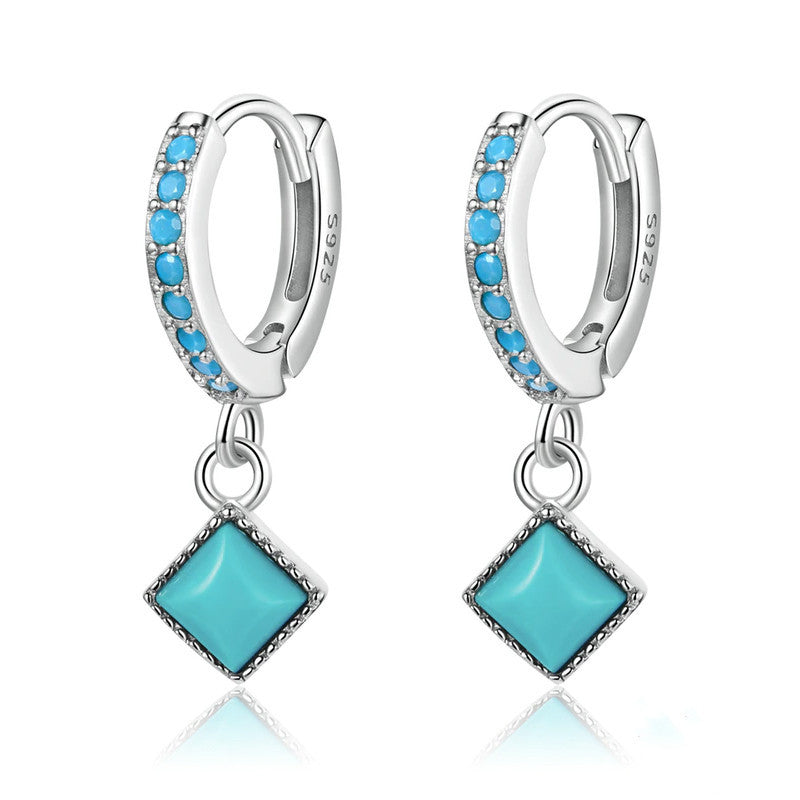 Silver hoop earrings with turquoise stones on a white background