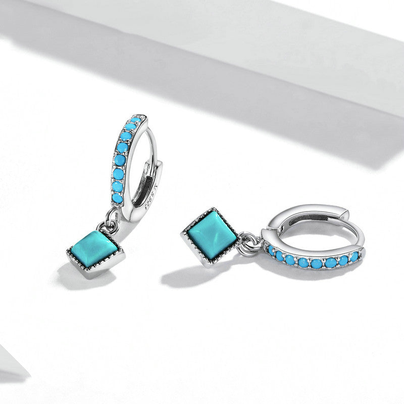 Pair of turquoise gemstone hoop earrings on a white background