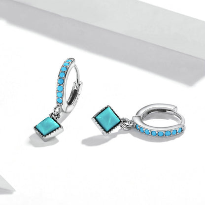 Pair of turquoise gemstone hoop earrings on a white background