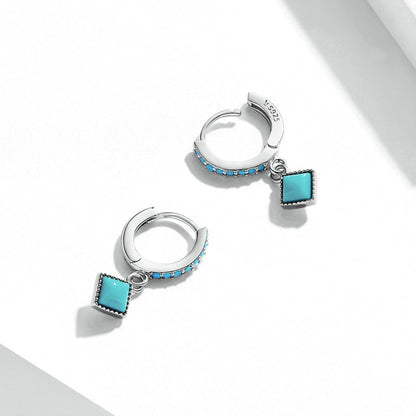 Silver hoop earrings with turquoise square charms on a white background