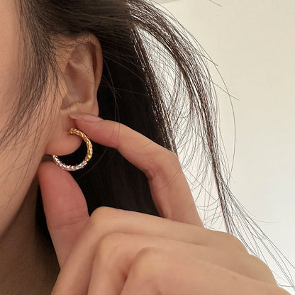 Close-up of a person wearing a two tone gold and silver hoop earring.