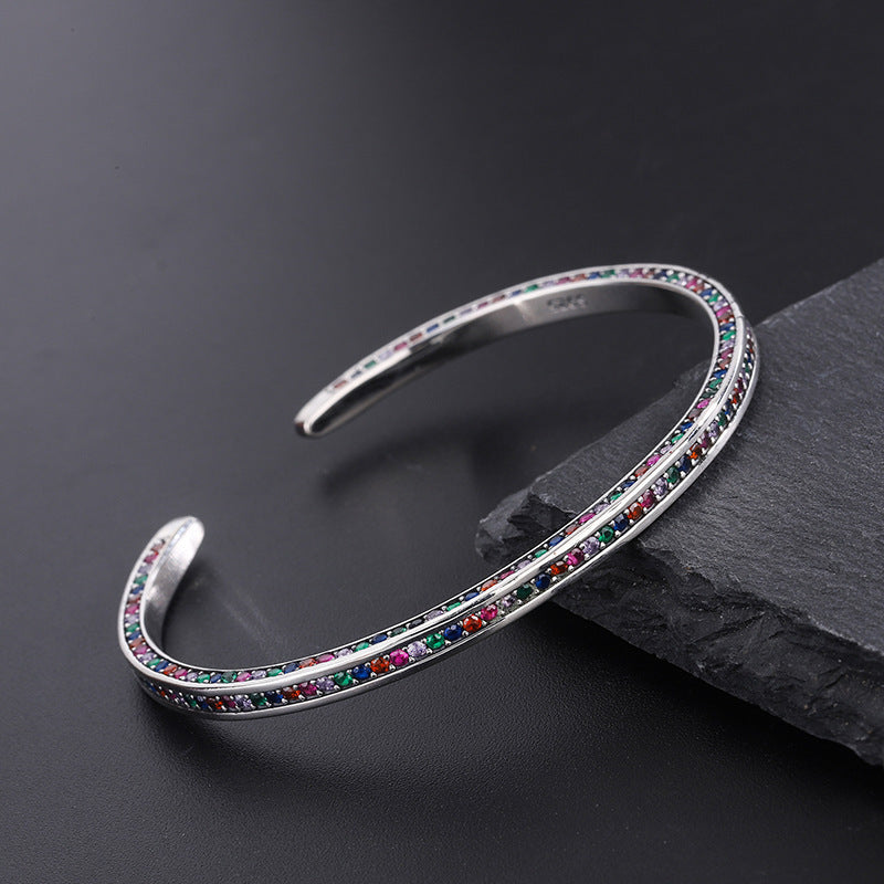 Silver bracelet with colorful stones on a dark surface