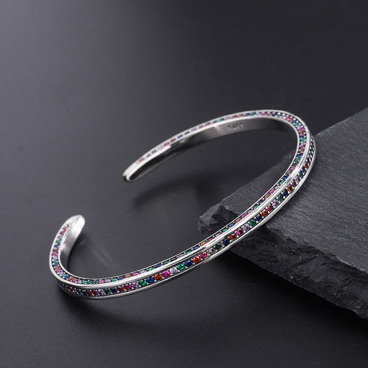 Silver bracelet with colorful stones on a dark surface
