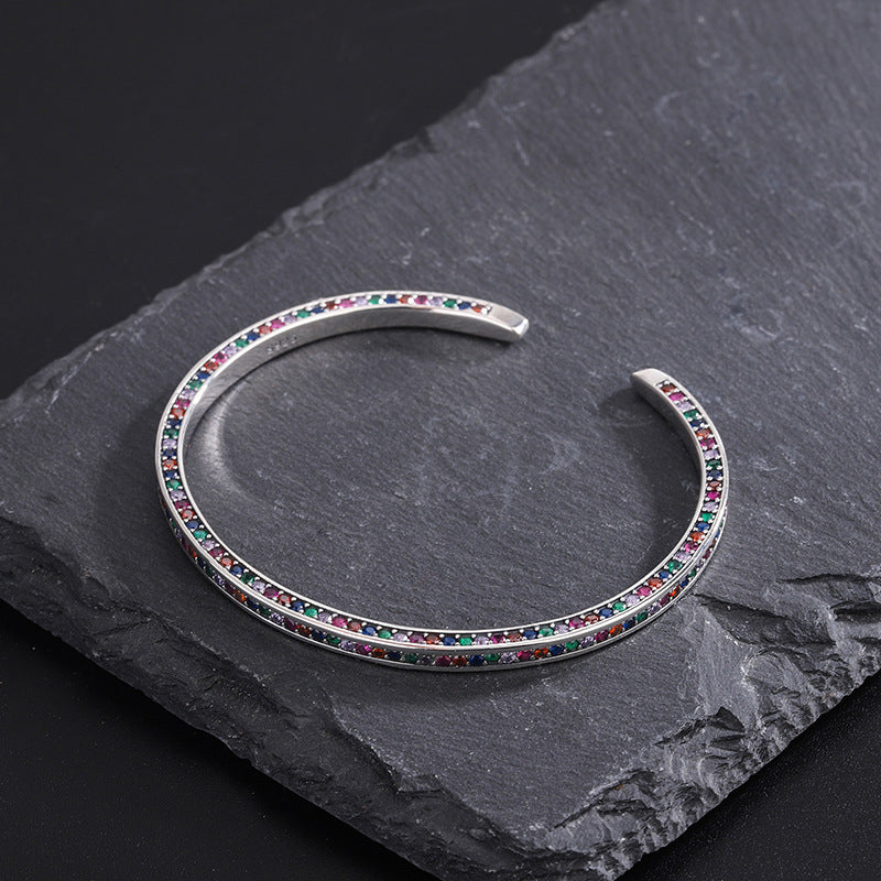 Silver bracelet with colorful stones on a dark stone surface
