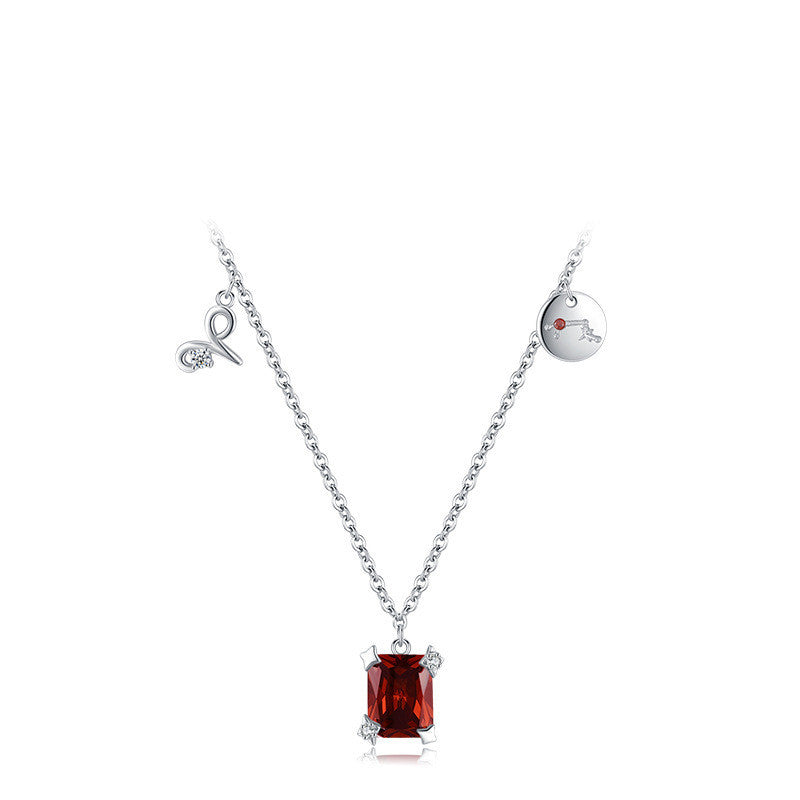 Silver necklace with a red gemstone pendant on a white background