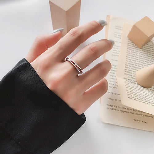 Hand wearing a silver ring with a blurred book in the background