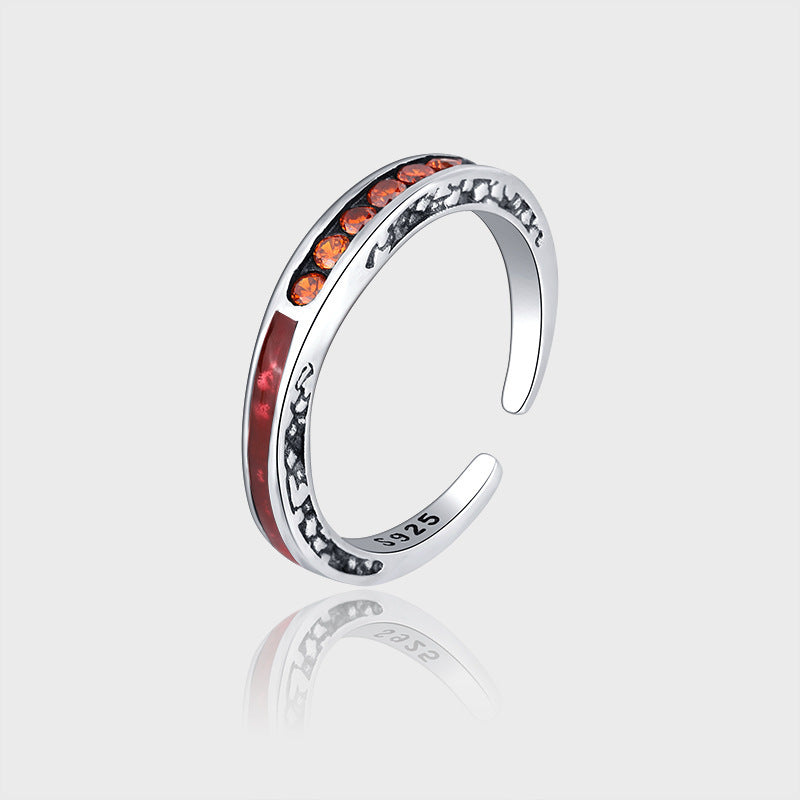 Silver ring with orange gemstones on a light gray background