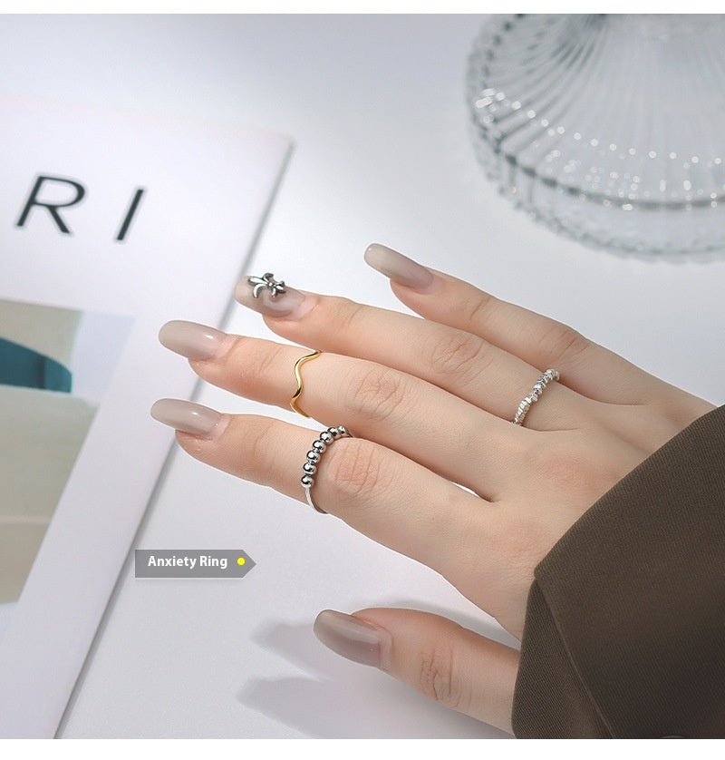 Close-up of a person's hand wearing the 925 sterling silver beaded anxiety ring while reading or relaxing.