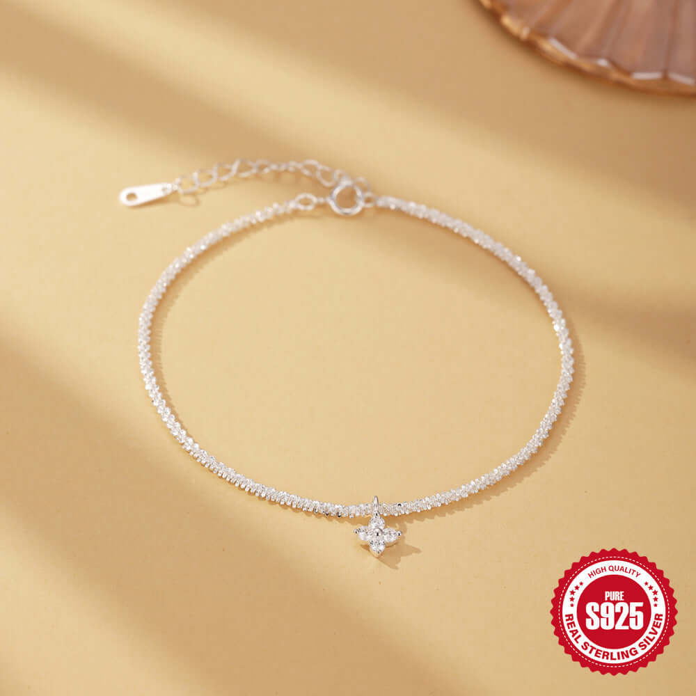 Silver anklet with a flower charm on a beige background, featuring a '925 Sterling Silver' stamp.
