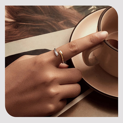 Hand with a ring holding a cup of coffee on a wooden table