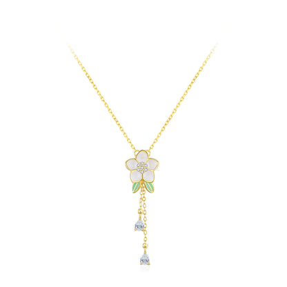 Gold necklace with a white flower pendant on a white background.