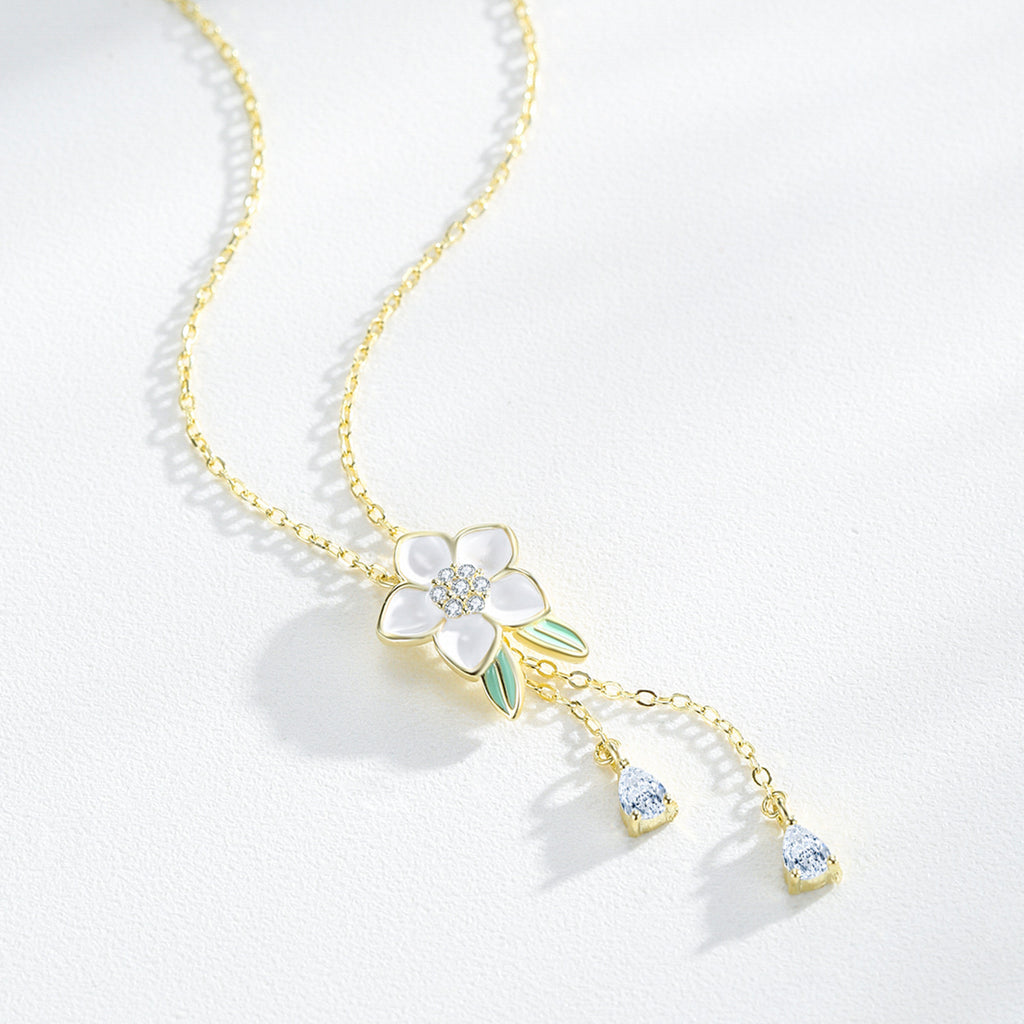Delicate gold necklace with floral pendant on a white background.