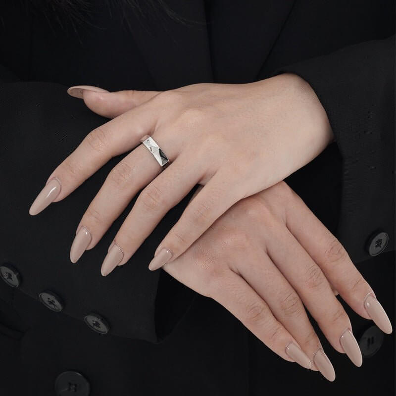 Close-up of hands with a silver hexagonal ring on a black background
