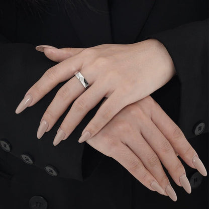 Close-up of hands with a silver hexagonal ring on a black background