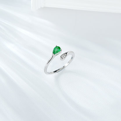 Silver ring with a green emerald gemstone and small zircon diamonds on a white background