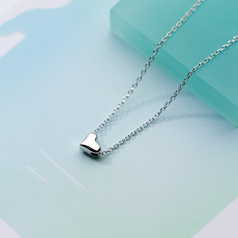 Silver heart-shaped pendant necklace on a light blue background